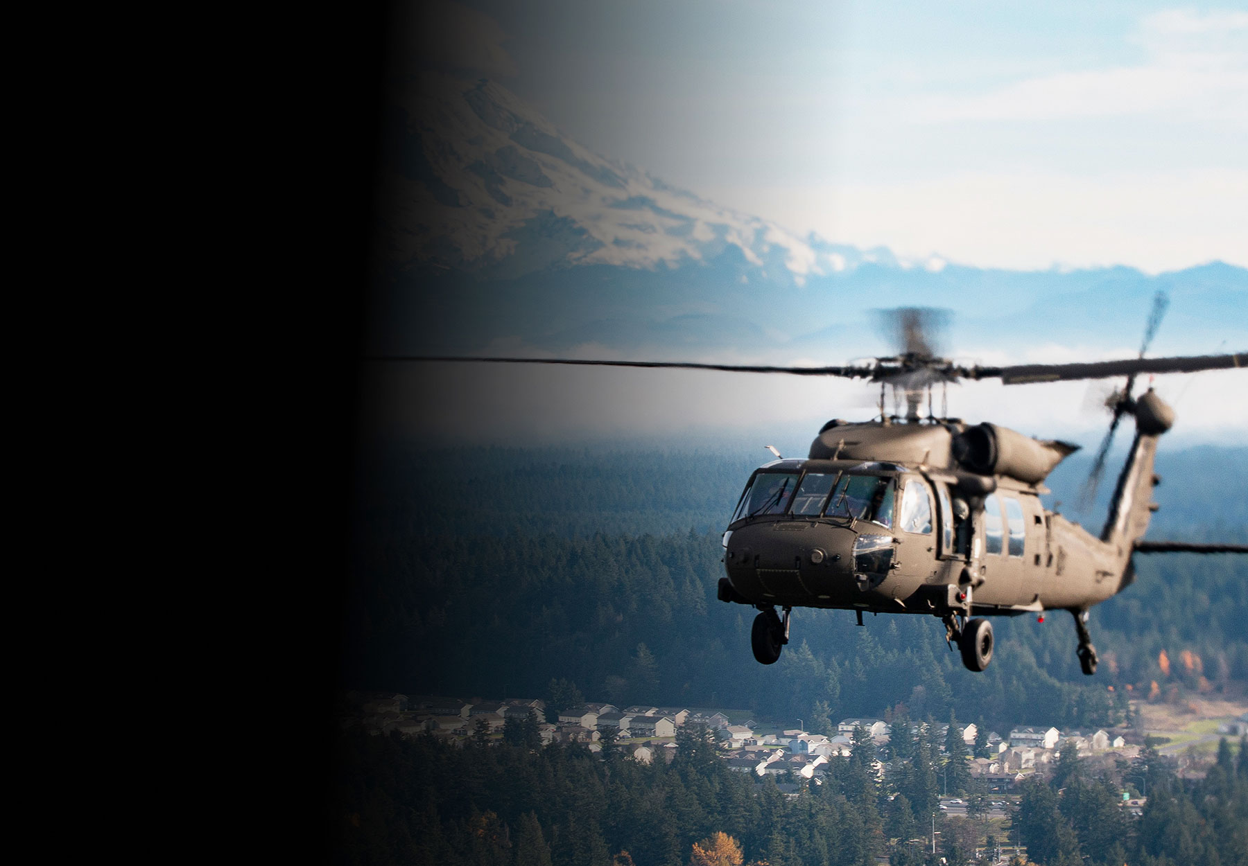 UH-60 Black Hawk helicopter in flight with snow-capped mountain in the background