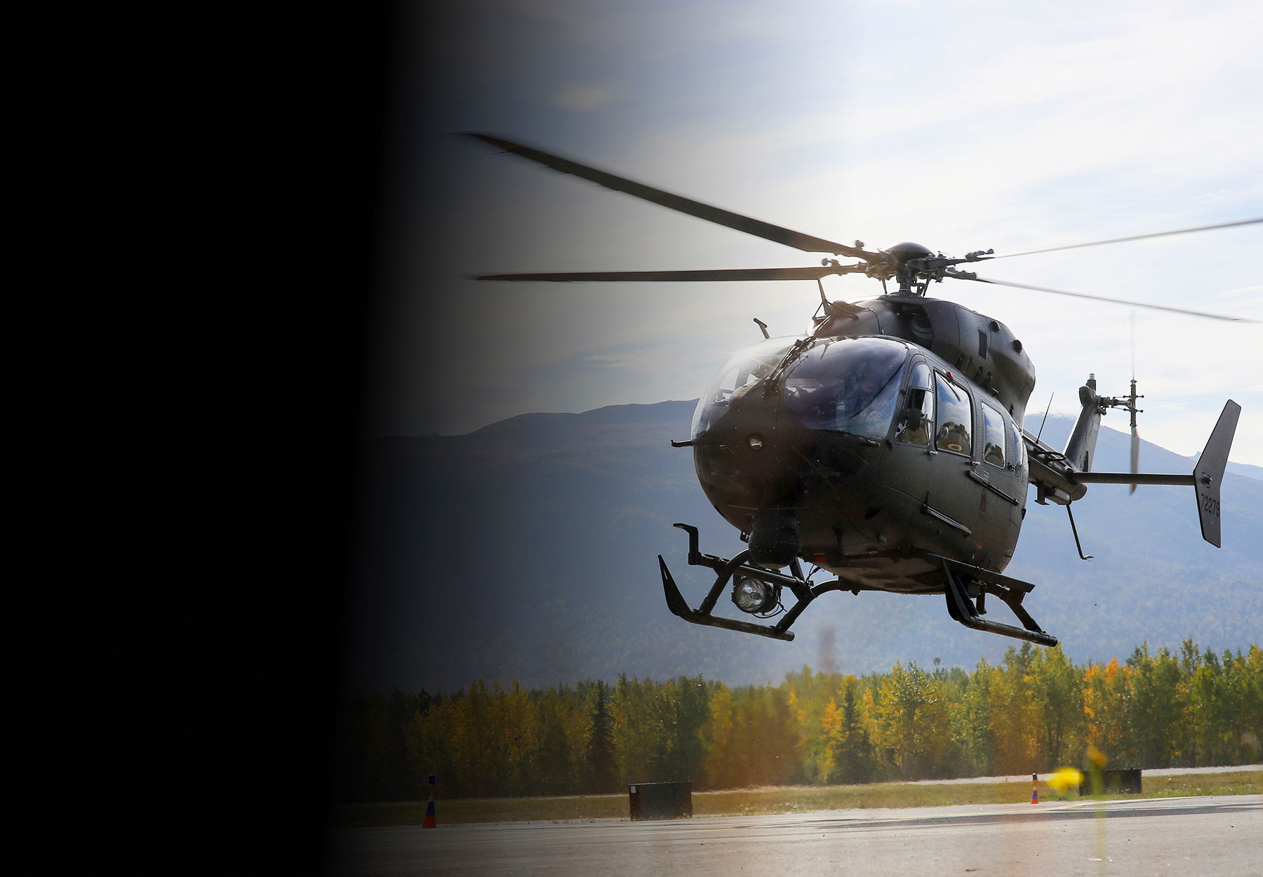 UH-72A Lakota helicopter hovering above ground with mountains in the background