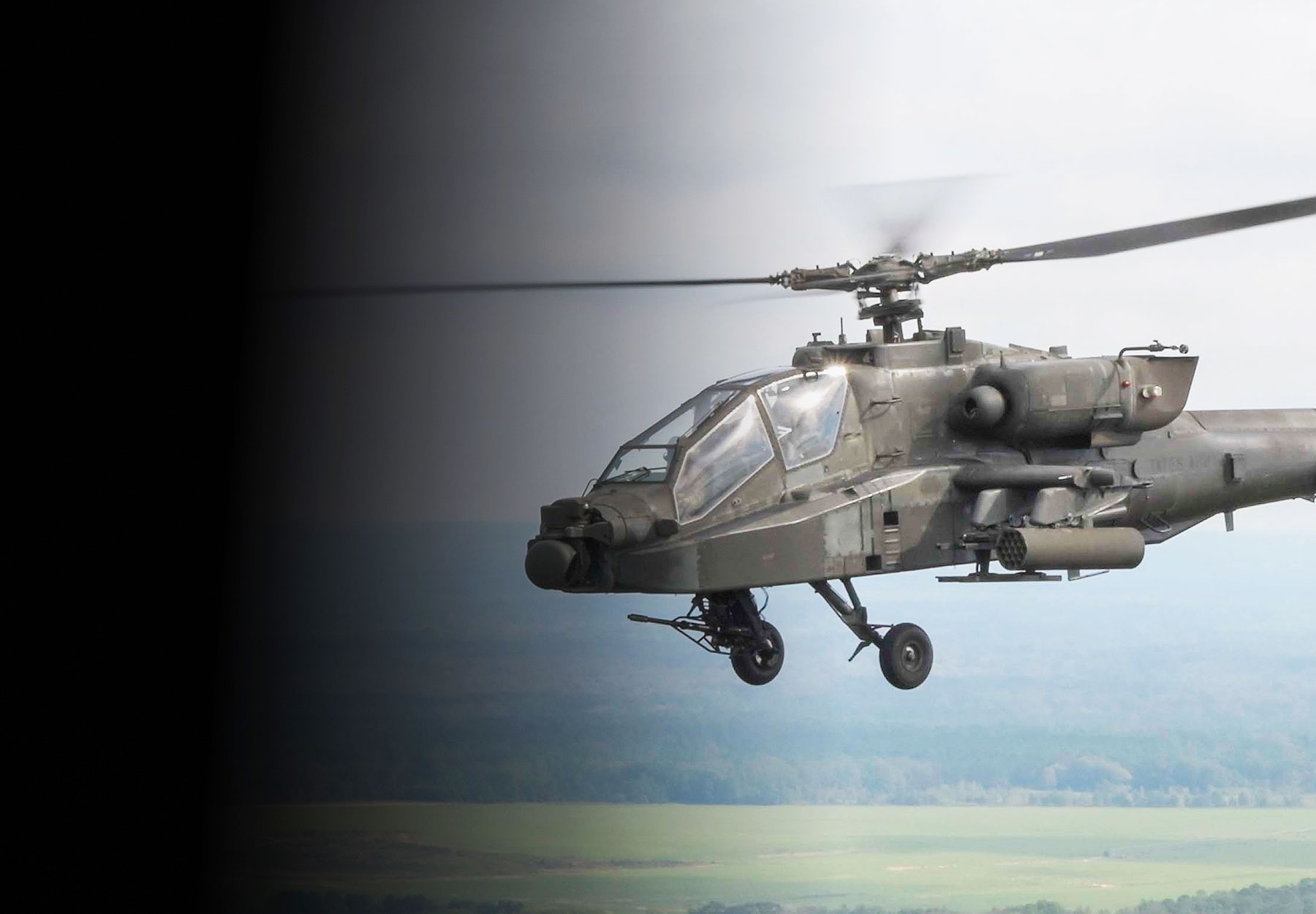 Two AH-64 Apache helicopters in flight above green landscape