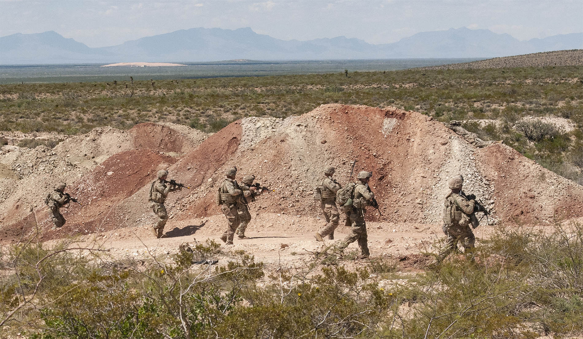 Multiple Soldiers on a patrol in the desert.